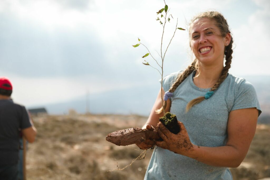 An international volunteer holds a tree that is about to planted